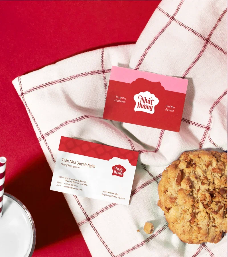 Brand collateral: business cards in the new system on a checked tablecloth beside a cookie